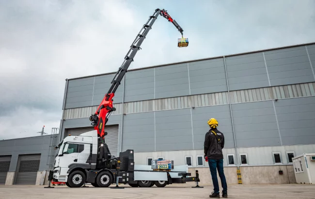 Camion grue en action soulevant une charge lourde dans un environnement de chantier