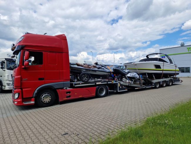 Camion transportant des bateaux et jet-skis sur une remorque, prêt à être livré